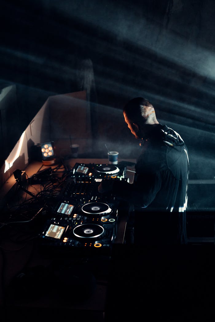 why-choose-us DJ mixing tracks at a dimly lit venue with advanced sound mixer equipment.