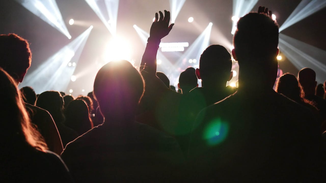 A vibrant concert scene with a silhouetted crowd, lights and excitement.